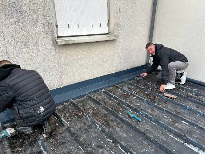 Couvreur en train de démousser une toiture dans le Loiret